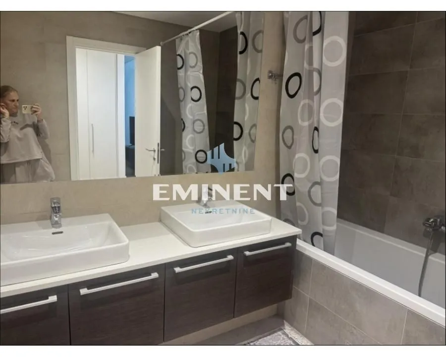Bathroom with double sinks, bathtub, and a large mirror.