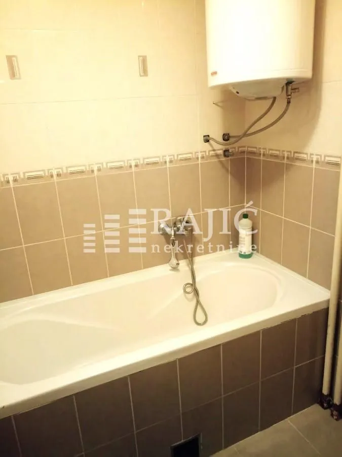 Small bathroom with a bathtub and a water heater.