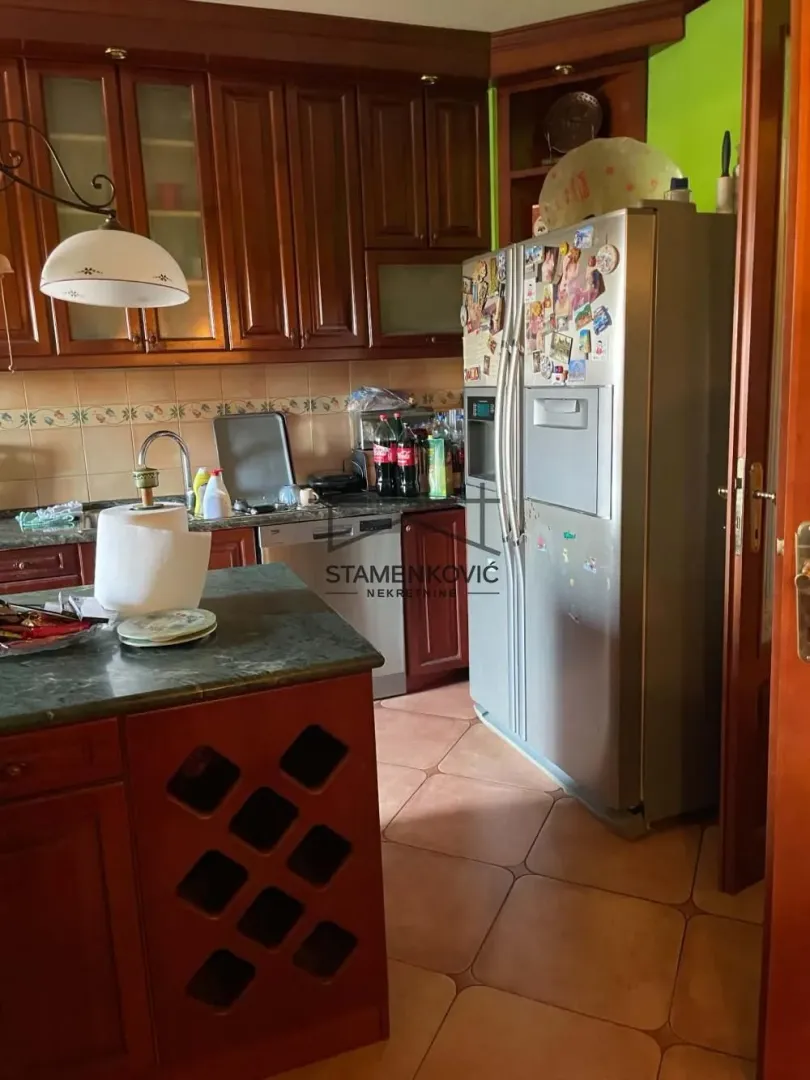 Tradicionalna kuhinja sa drvenim elementima i velikim frižiderom.