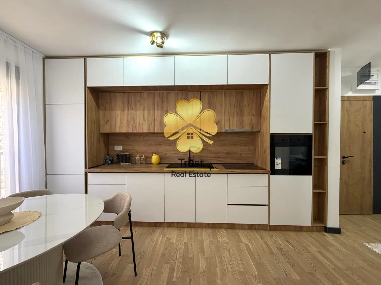 Modern kitchen with white and wood elements and a dining table.