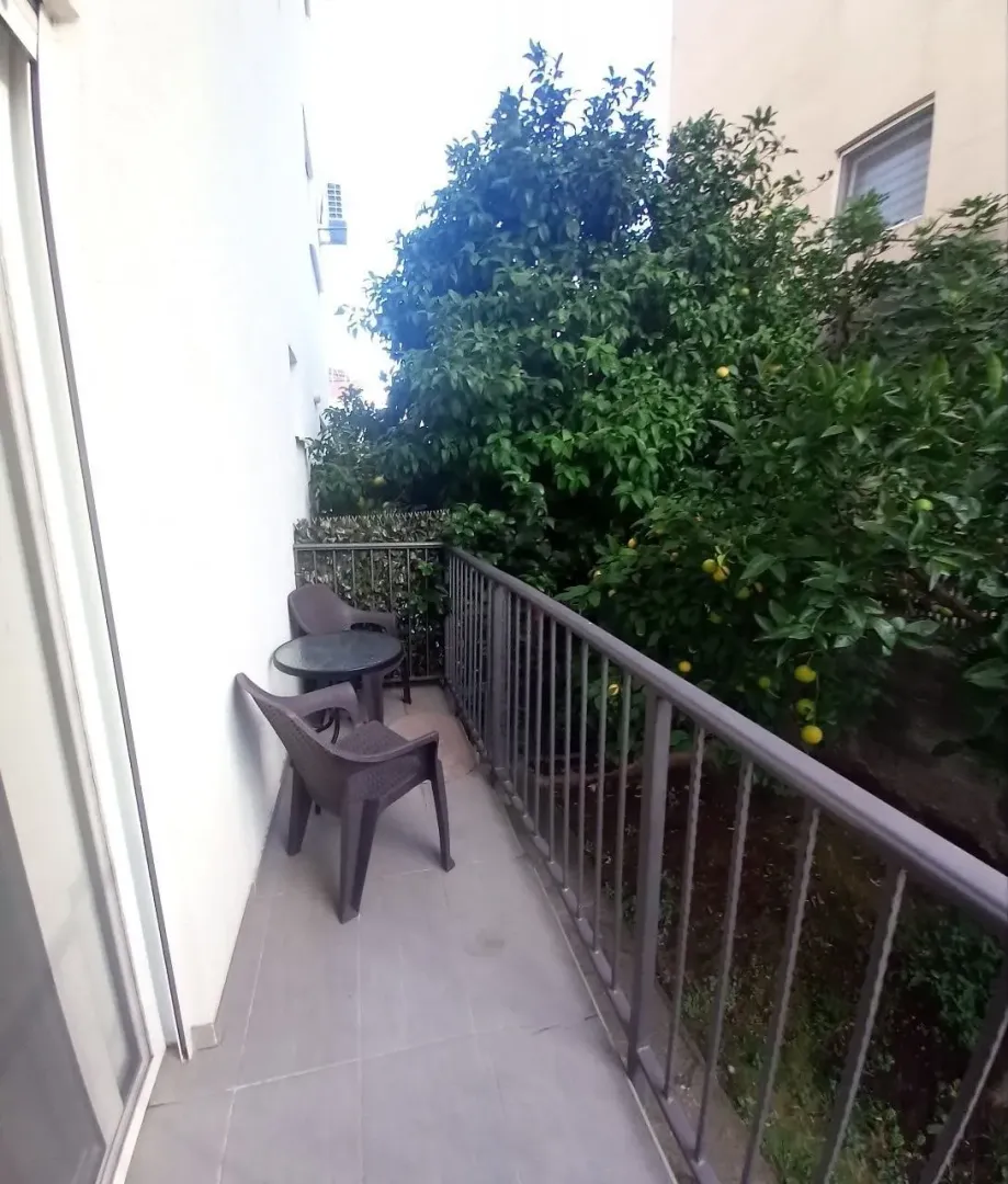 Small balcony with seating furniture and a view of greenery.