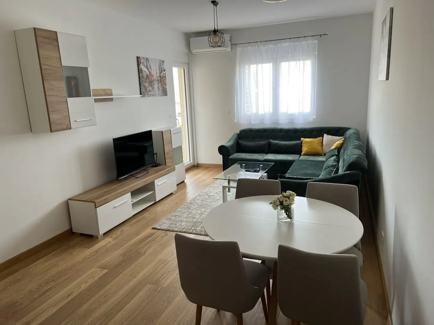 Bright living room with a dining table and a green corner sofa.