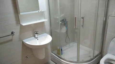 Bathroom equipped with a shower cabin, washbasin, and toilet. - image 17