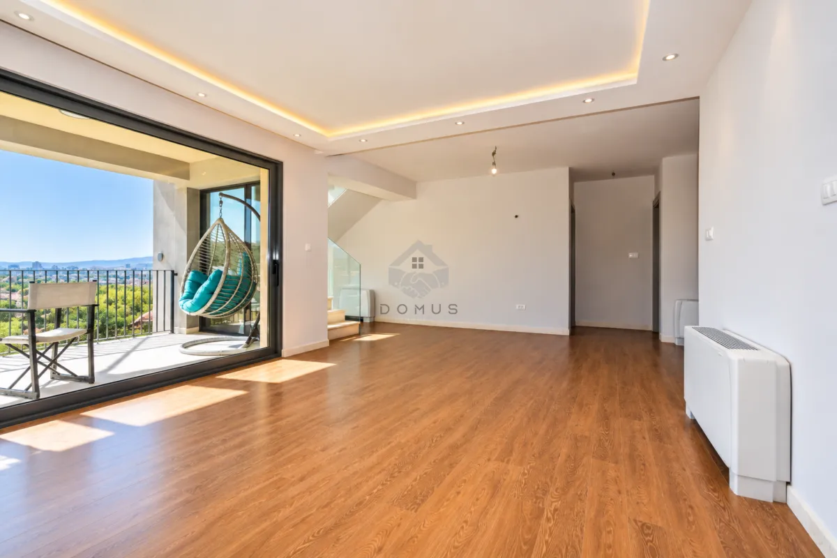 Spacious empty living room with access to the terrace and wooden flooring.