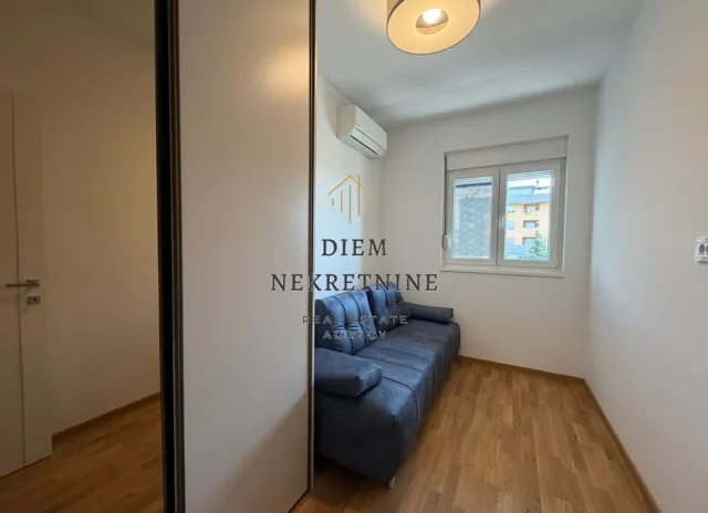 Smaller living room with a blue sofa and hardwood flooring.