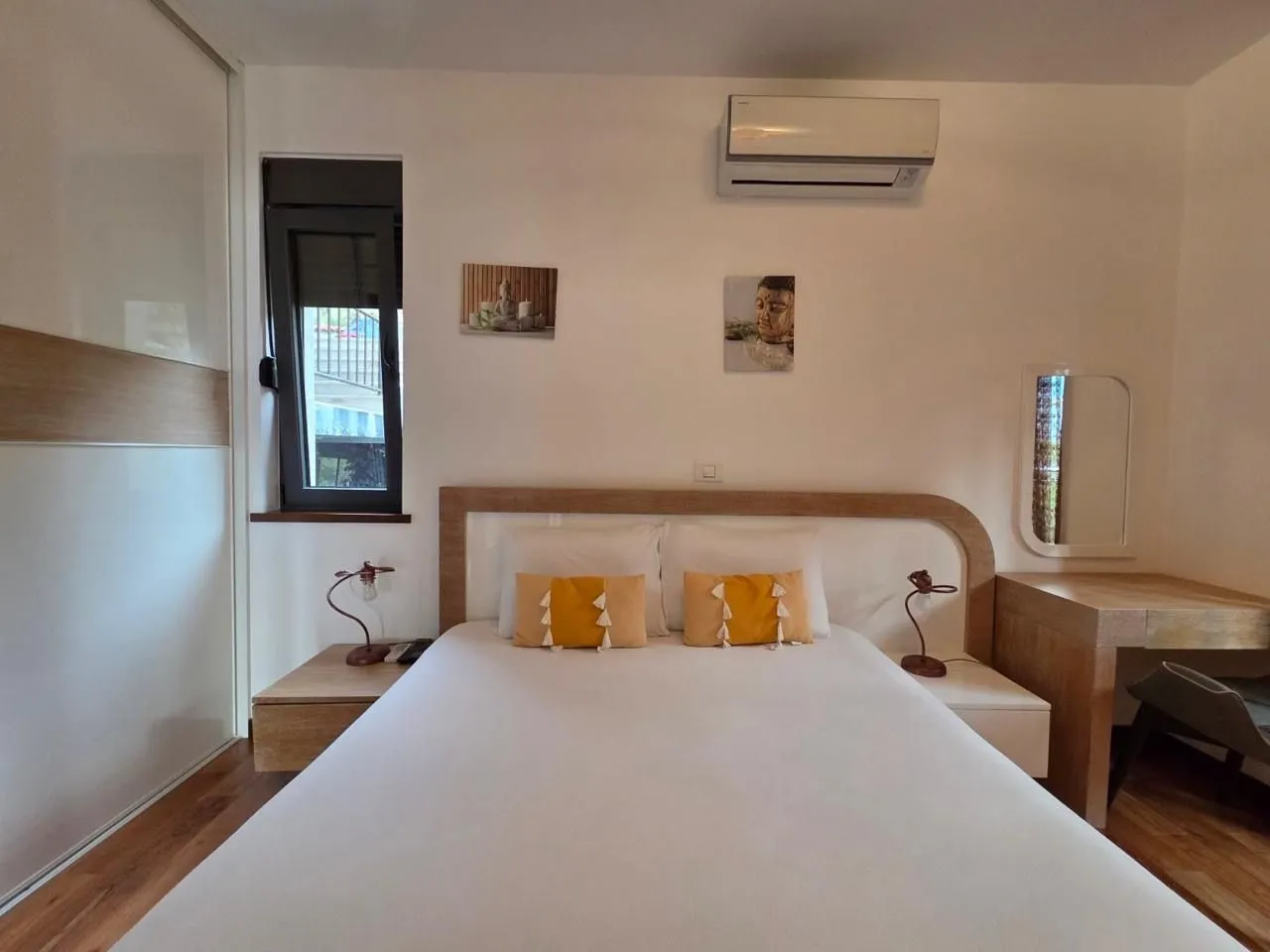 Bright bedroom with a double bed, wardrobe, and air conditioning.