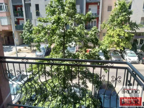 Pogled sa balkona na drveće i parking ispred zgrade. - image 3