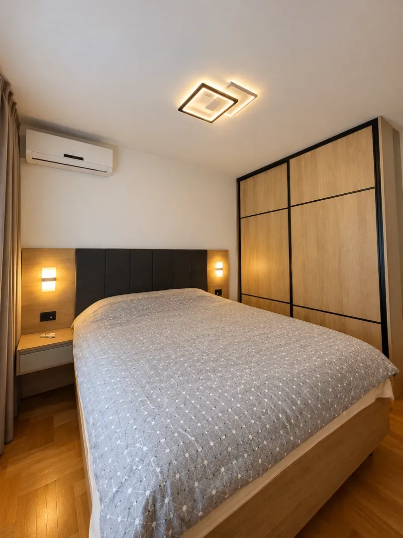 Bedroom with a double bed, fitted wardrobe, and air conditioning unit.