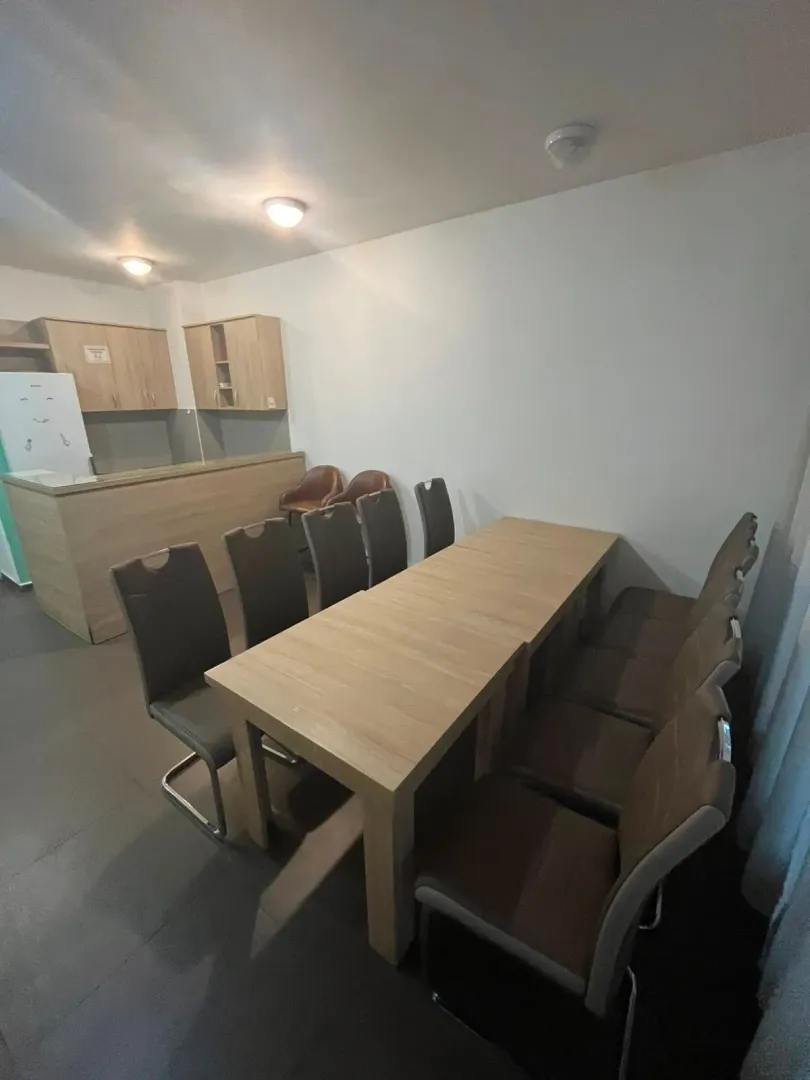 Dining area with a large table and chairs and part of the kitchen in the background.