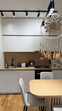 Moderna kuhinja sa bijelim elementima i drvenim radnim dijelom. - image 3