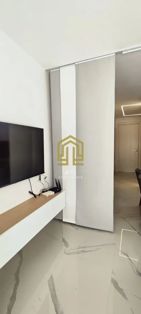 Pogled na dnevni boravak sa televizorom i komodom.