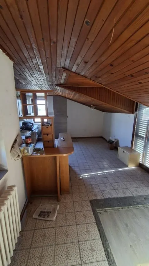Kuhinja sa drvenom lamperijom na plafonu i pločicama na podu.