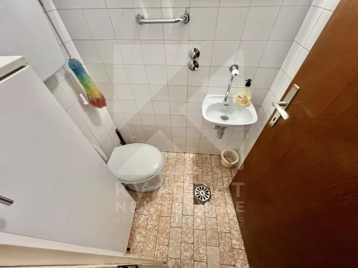 Small bathroom with a toilet, washbasin, and white tiles.