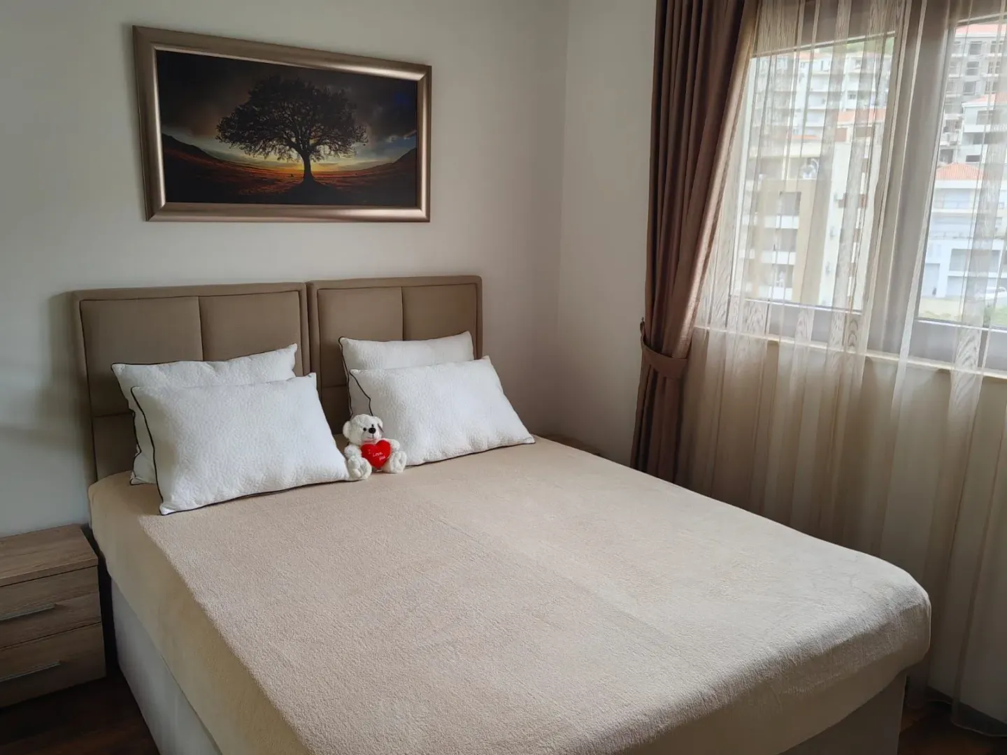 Bedroom with a double bed, nightstand, and window with curtains.