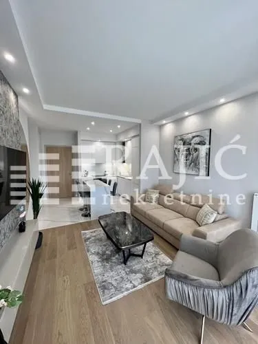 Modern living room with a sofa and a view towards the kitchen.