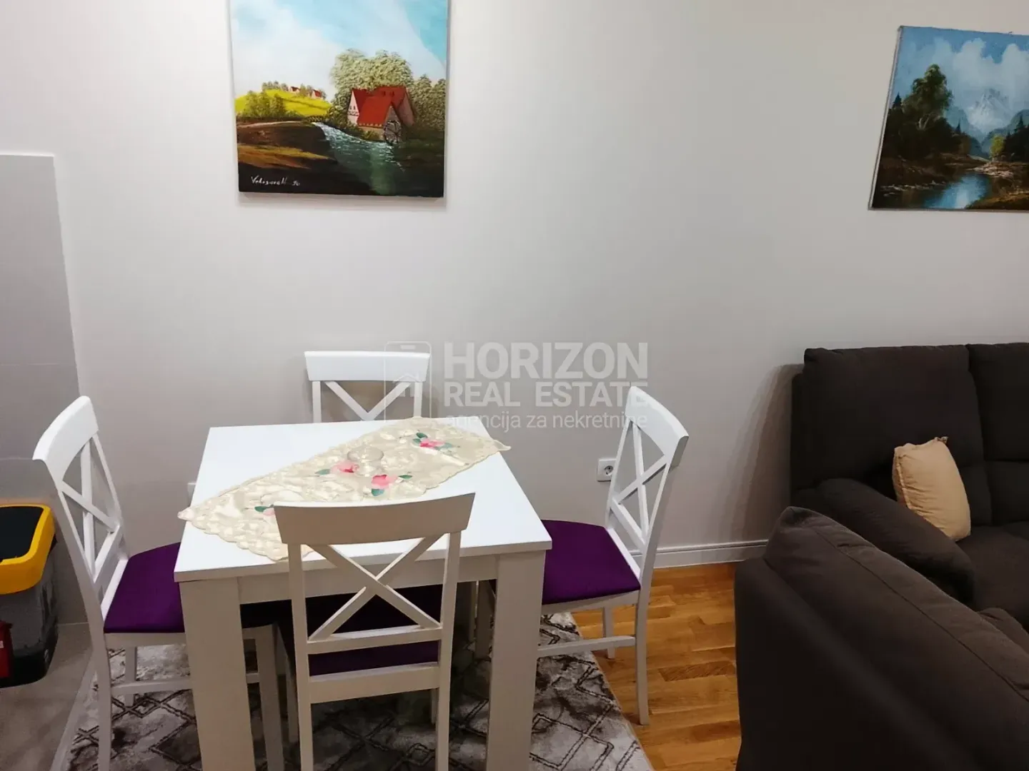 Dining table with white chairs and part of the sofa set in the living room.