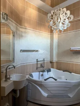 Kupatilo opremljeno ugaonom kadom, umivaonikom, ogledalom i ukrasnim lusterom. - image 12
