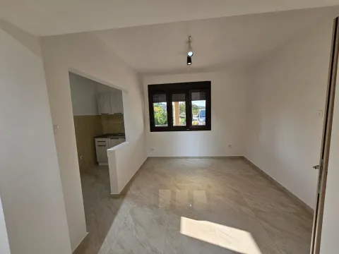 Bright empty room with tiled floors and a kitchen alcove. - image 7