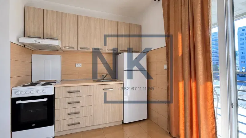 Small kitchen with wooden cabinetry, stove, and refrigerator.