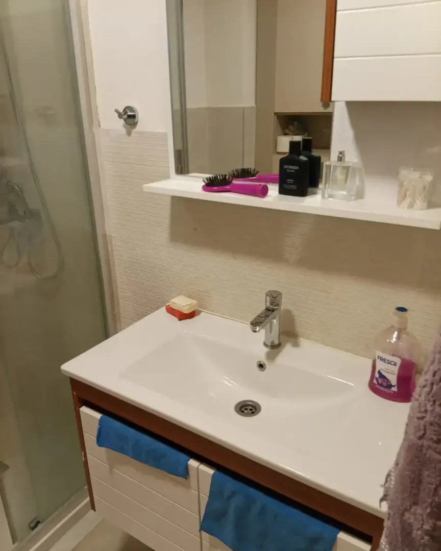 Bathroom with a washbasin, mirror and shower cabin.