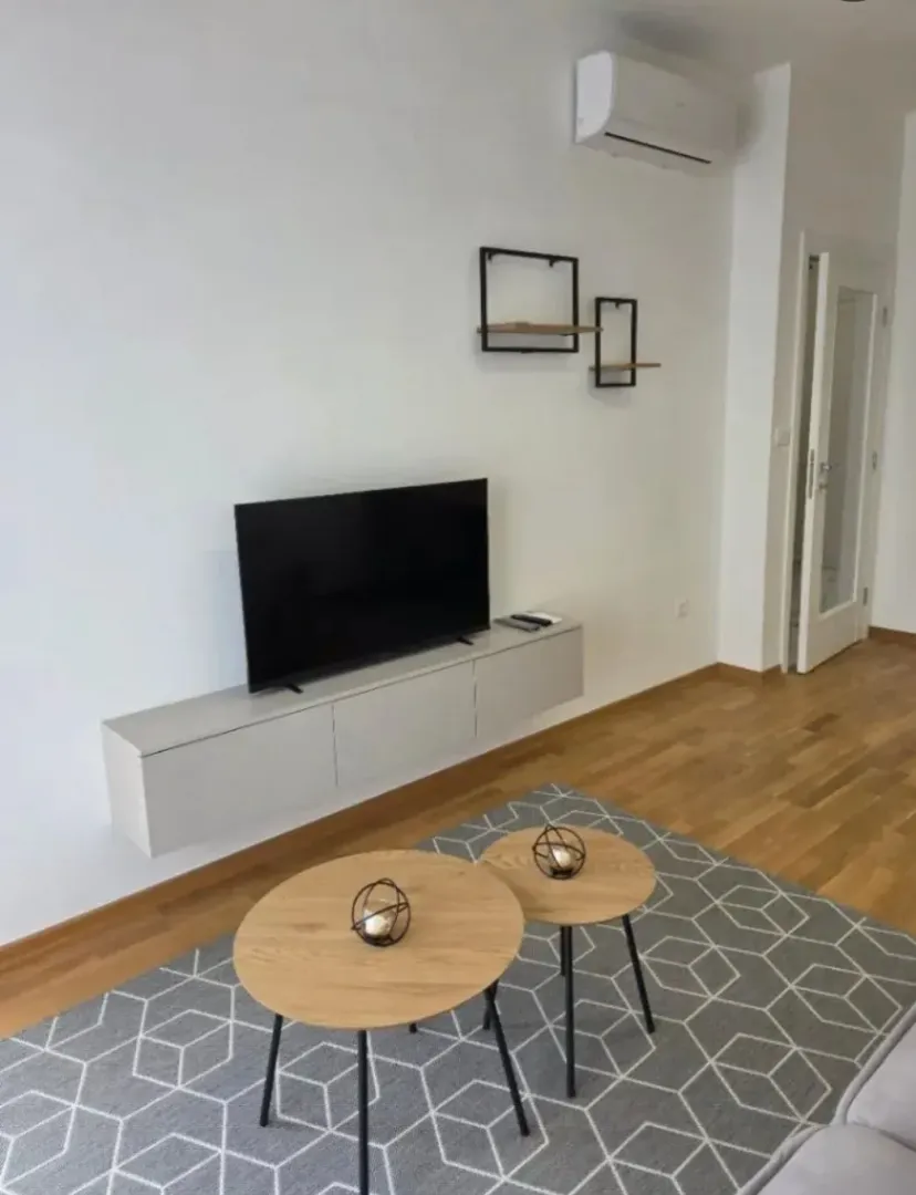 Living room with a TV, coffee tables, and hardwood flooring.