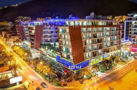 Night view of the exterior of a mixed-use building with highlighted commercial spaces. - image 2