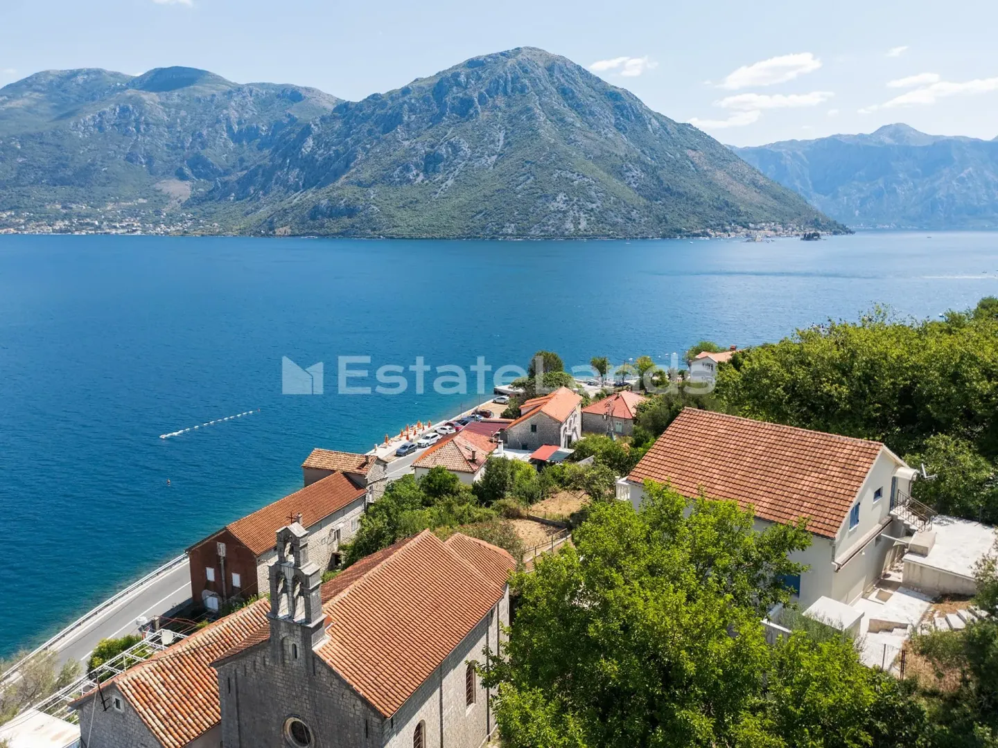 Pogled iz vazduha na priobalno naselje sa kamenim kućama i pogledom na more.