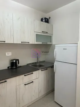 Compact kitchen with light wood cabinets and a white refrigerator. - image 9