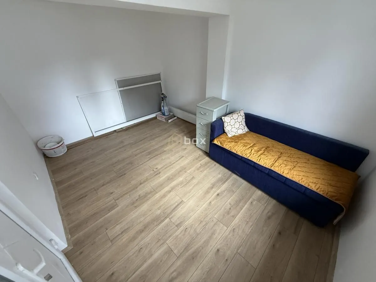 Small room with a blue sofa, wooden flooring, and white walls.