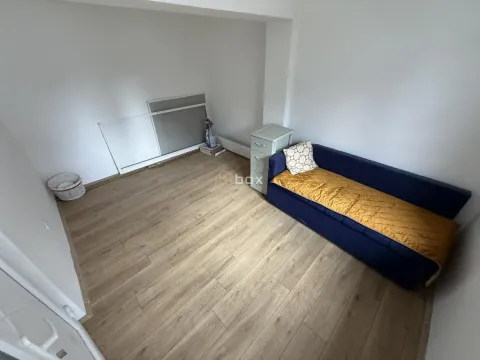 Small room with a blue sofa, wooden flooring, and white walls. - image 4