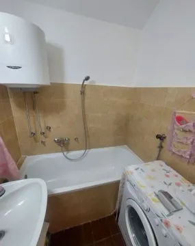 Bathroom equipped with a bathtub, washbasin, and washing machine. - image 9