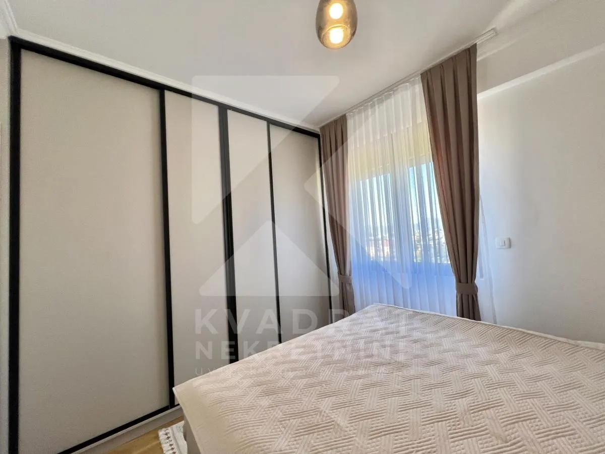 Bedroom with a large built-in wardrobe and a window with curtains.
