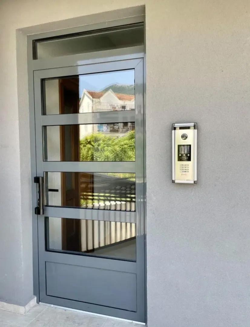 Glavni ulaz u zgradu sa interfonom i staklenim vratima.