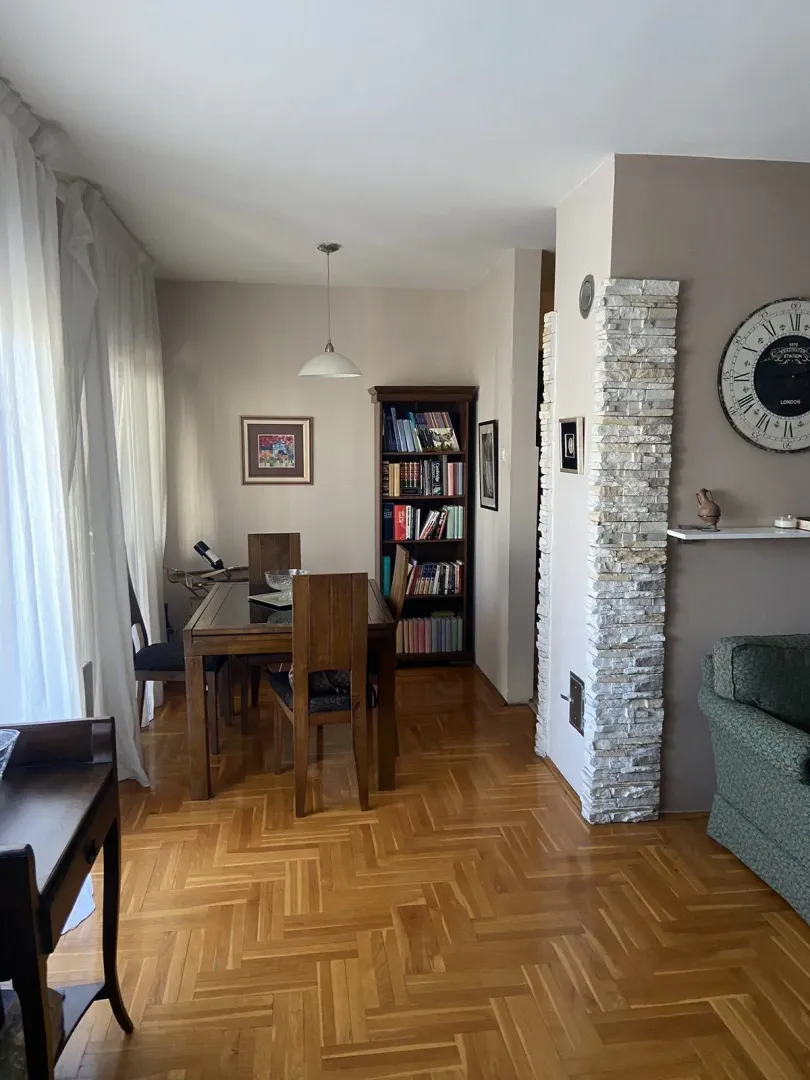 Bright dining area within a living space featuring wooden furniture and parquet flooring.