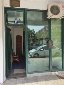 Entrance to a commercial space with a glass storefront and green frame. - image 2