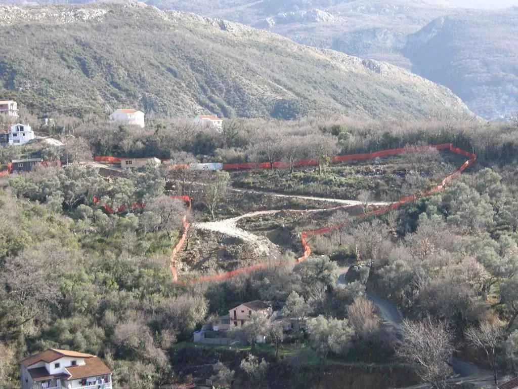 Pogled na ograđeni plac na brdu okružen prirodom i zelenilom.