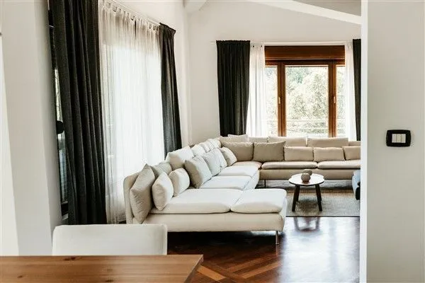 Bright living room featuring a large sectional sofa and parquet flooring.