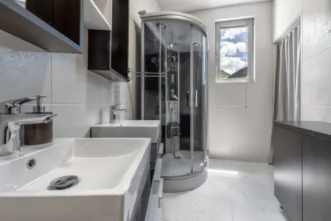 A modern bathroom equipped with a shower cabin and double washbasins. - image 22