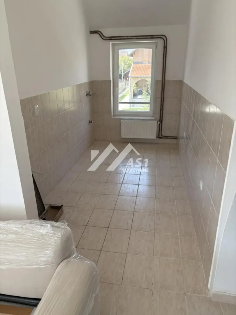 Empty kitchen with tiled floors and walls and a window.