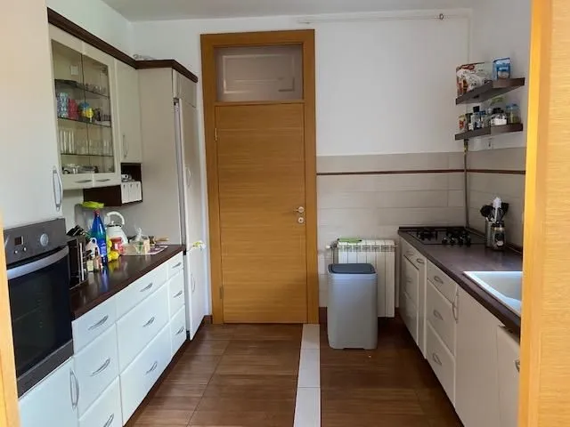 Small kitchen with white cabinets, countertop, and a wooden door.