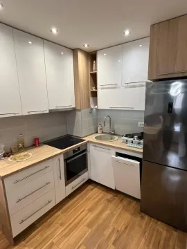 Small, modern kitchen with white cabinets, wooden countertops, and a refrigerator. - image 7