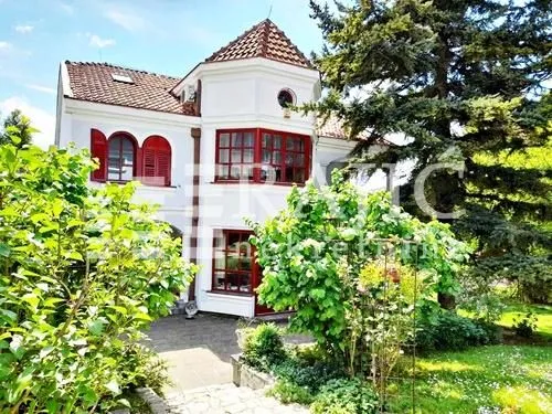 Exterior view of the house with a yard and greenery.