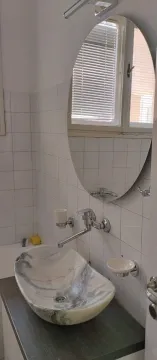 Kupatilo sa upečatljivim mermernim lavaboom i ovalnim ogledalom. - image 7