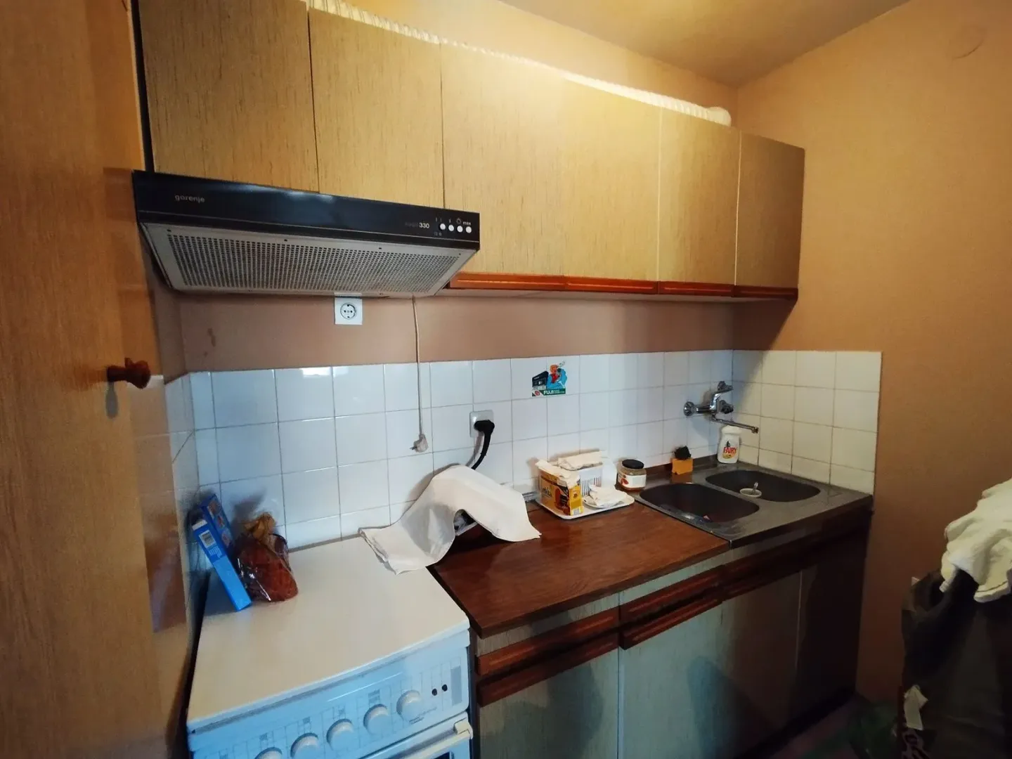 Manja kuhinja sa elementima od drveta, šporetom i sudoperom.