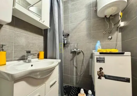 Small bathroom with a sink, shower cabin, and washing machine. - image 9
