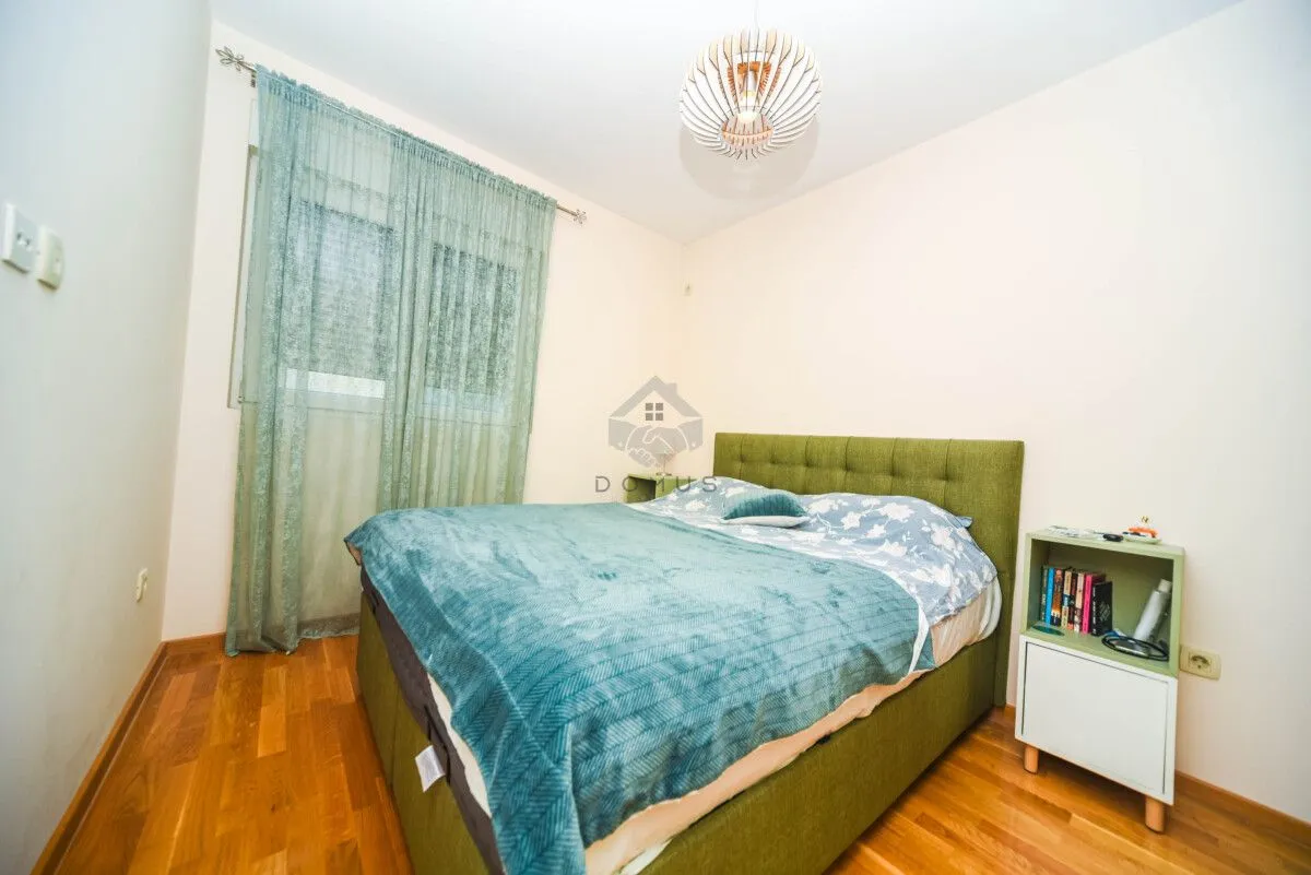 Furnished bedroom with a double bed, bedside table, and window.