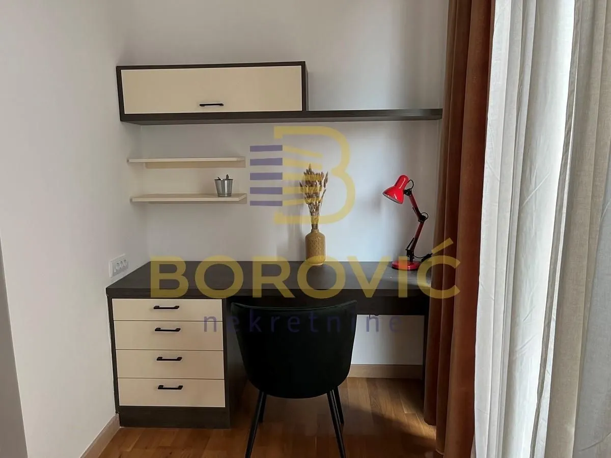 A desk with a chair and wall units in the room.