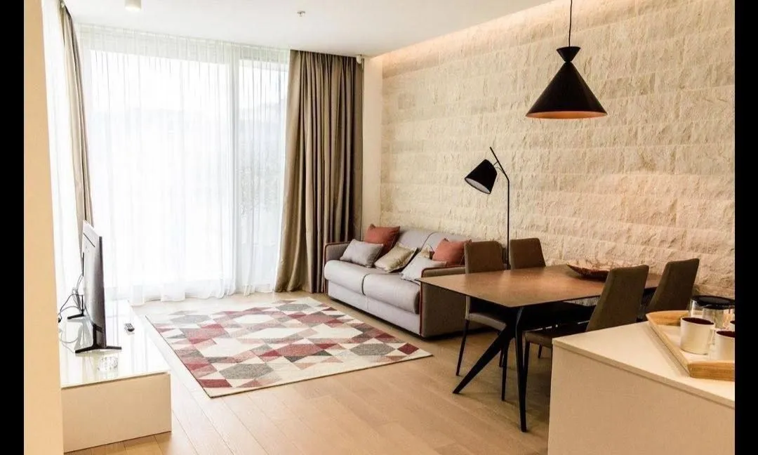 Modern living room with dining area and a stone wall.