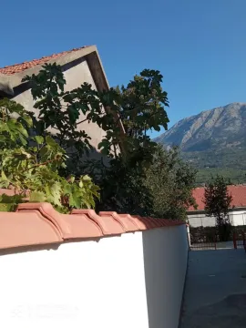 Eksterijer kuće sa dvorištem, ogradom i pogledom na planinu. - image 2
