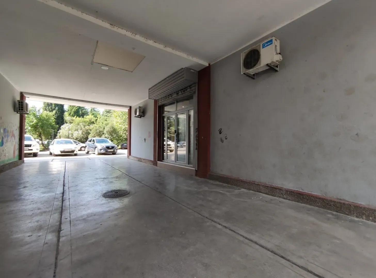 Covered driveway and entrance to a commercial space with glass doors.